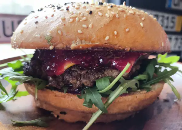 Burger z bekonem, sałatą i serem na drewnianym talerzu